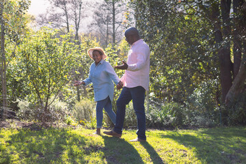 Happy african american senior couple walking, holding hands outdoors - Powered by Adobe