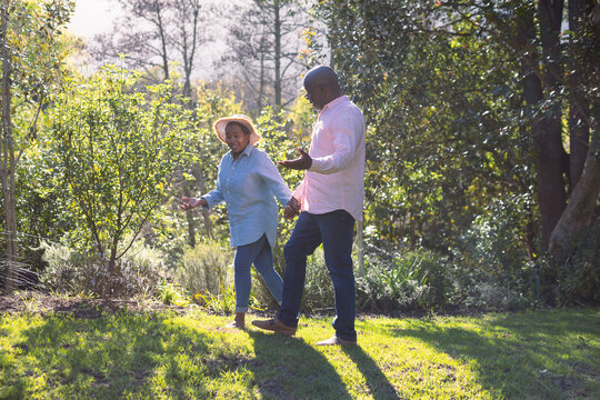 Happy african american senior couple walking, holding hands outdoors