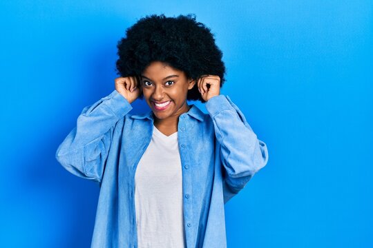 Young african american woman wearing casual clothes smiling pulling ears with fingers, funny gesture. audition problem