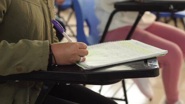 mano de Joven mujer, en escuela escribe en su cuaderno 