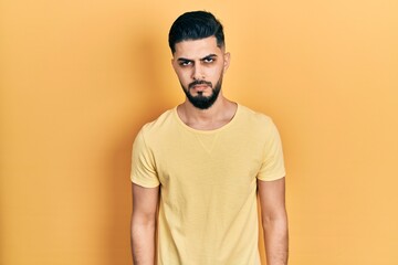 Handsome man with beard wearing casual yellow t shirt skeptic and nervous, frowning upset because of problem. negative person.