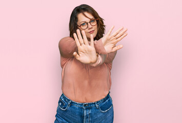 Young plus size woman wearing casual clothes and glasses rejection expression crossing arms and...