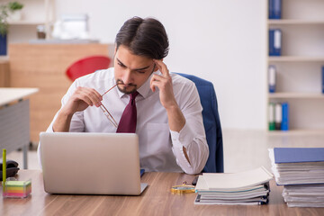 Young male employee and too much work in the office