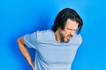 Middle age caucasian man wearing casual clothes suffering of backache, touching back with hand, muscular pain