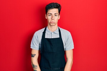 Young hispanic man wearing apron depressed and worry for distress, crying angry and afraid. sad expression.