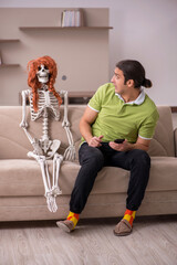 Young man sitting on the sofa with female skeleton