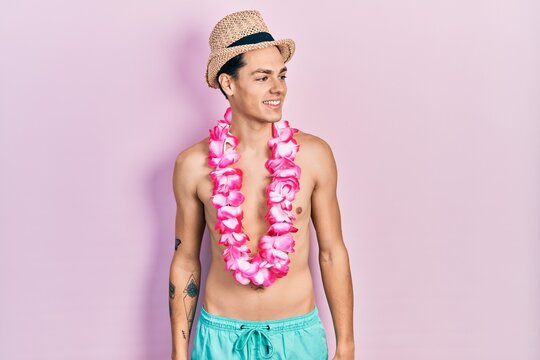 Young hispanic man wearing swimwear and summer hat looking to side, relax profile pose with natural face and confident smile.