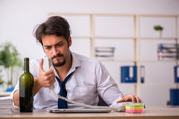 Young alcohol addicted employee sitting in the office