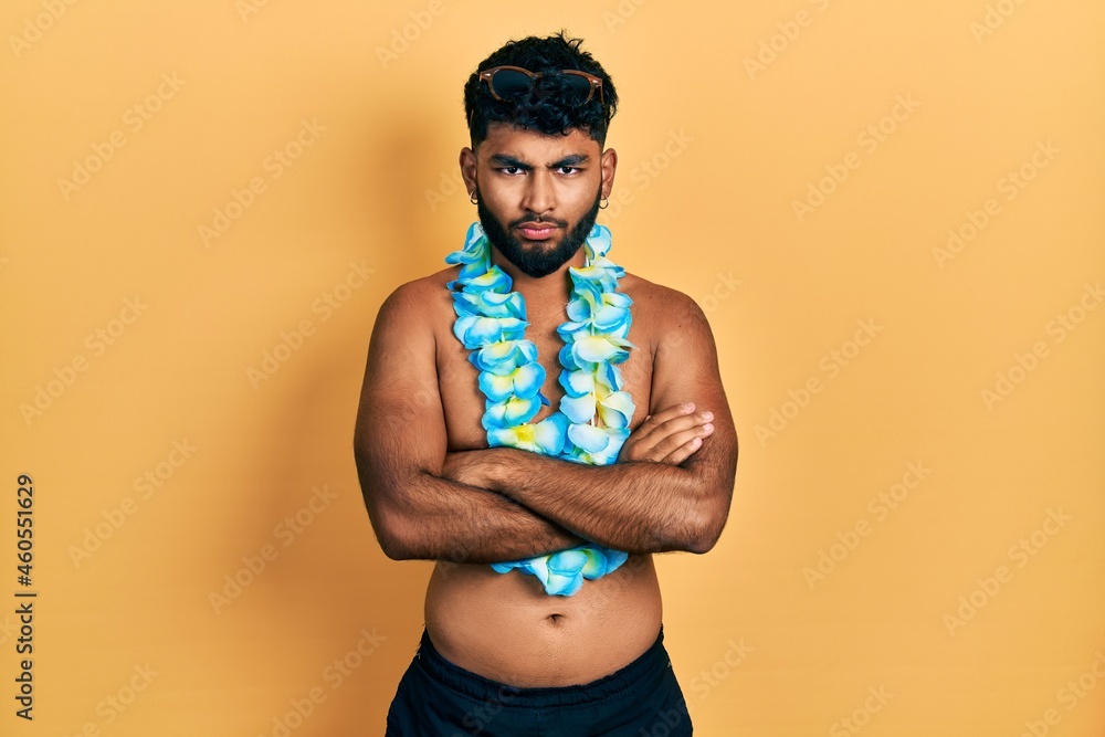 Poster arab man with beard wearing swimsuit and hawaiian lei skeptic and nervous, disapproving expression o