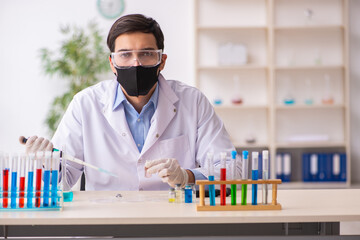 Young male chemist working at the lab during pandemic