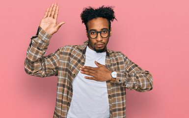 Young african american man with beard wearing casual clothes and glasses swearing with hand on...