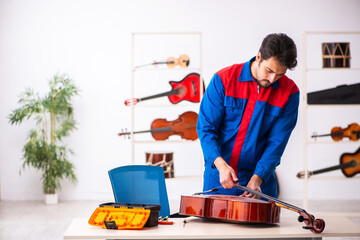 Young male repairman repairing musical instruments at workplace