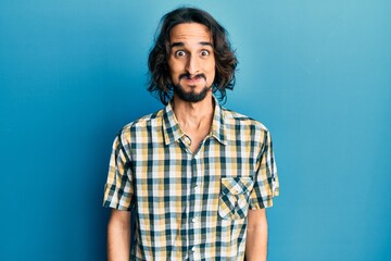 Young hispanic man wearing casual clothes puffing cheeks with funny face. mouth inflated with air, crazy expression.