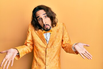 Young hispanic man wearing hipster elegant look clueless and confused expression with arms and...