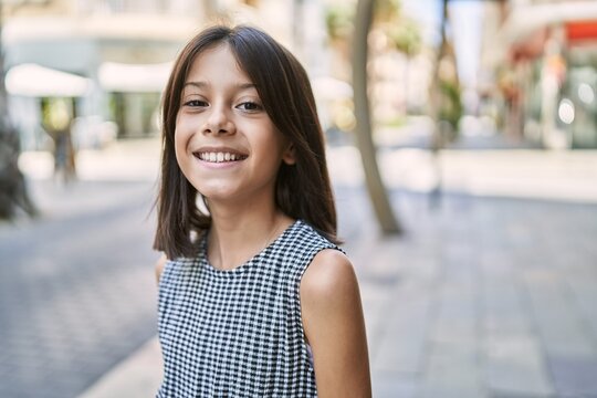 Young hispanic girl smiling outdoor at the town