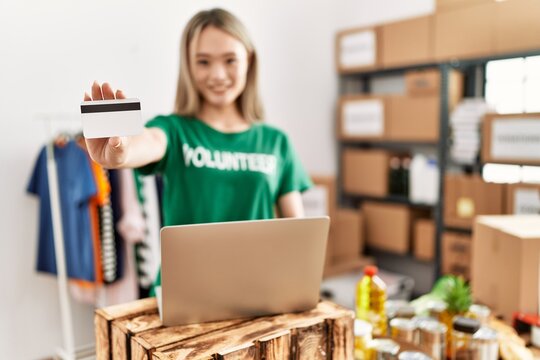 Young Chinese Woman Wearing Volunteer Uniform Holding Credit Card Working At Charity Center