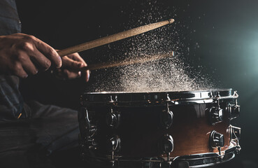 Close-up of a drummer playing a snare drum with splashing water.