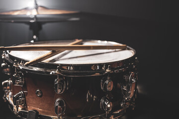 Part of a drum kit, snare drum on a dark background.