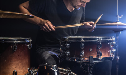 A male drummer plays drums on stage.