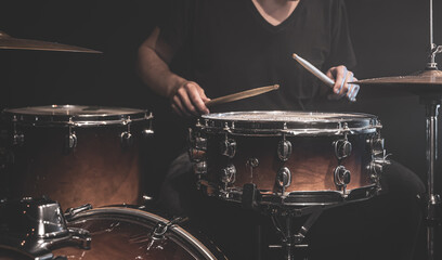 A male drummer plays a drum kit on stage.