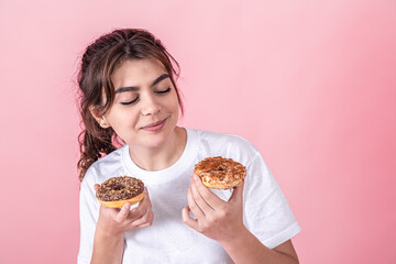 Portrait of a pretty, young woman showing donuts isolated over pink background.