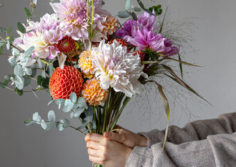 A woman is holding a festive bouquet with chrysathemum flowers in her hands.