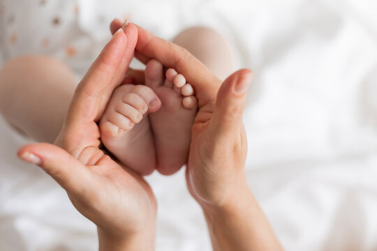 closeup of the bare feet of a newborn baby in his mother's hands on a white background. top view. caring for a newborn. mother's love. space for text. High quality photo