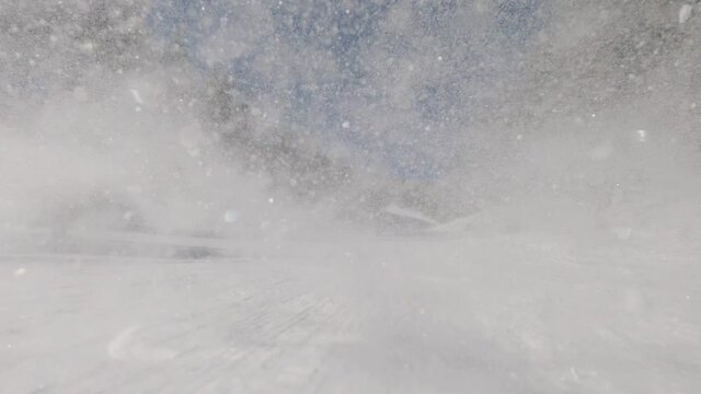 Male snowboarder spraying camera with snow, handheld
