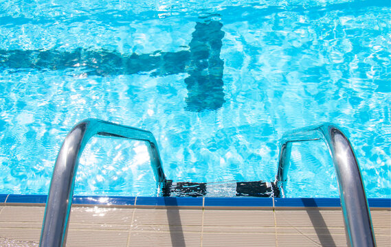 sports outdoor pool with a ladder with blue water sparkling in the sun