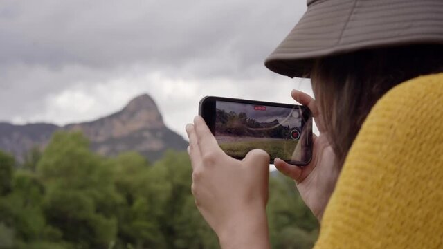 Woman taking pictures of the mountains with her mobile phone of the landscape in nature.