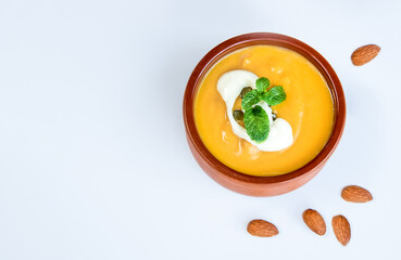 yellow pumpkin soup served and ready with bread, two pieces of raw pumkin in the background, thanksgiving or winter meal, traditional autumn food. 