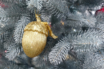 Christmas tree branch decorated with a golden acorn figurine 