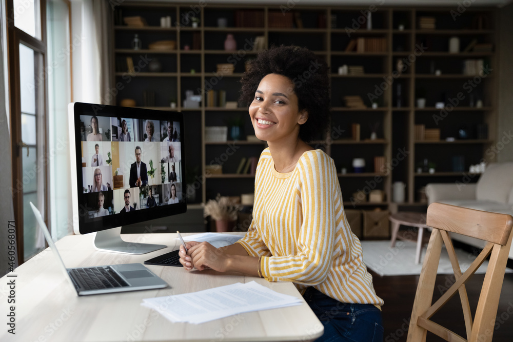 Canvas Prints Portrait of smiling beautiful millennial african american biracial woman sitting at table in modern office, holding video call meeting with group of diverse employees, distant communication concept.