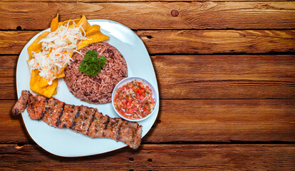 Roast beef with gallo pinto and pico de gallo, Nicaraguan food served on wooden table, Plate with...