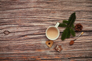 Directly above shot of coffee cup, pine branch, cookies and cinnamon on wooden background