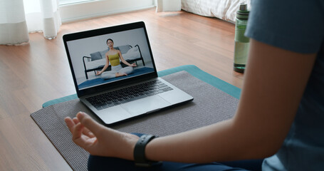 Close-up asia people woman enjoy study happy watch live video sit on sport mat at cozy home floor indoor easy zen class. Body calm life stress relax asana lotus pose in laptop self learn online media.