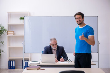 Old male teacher and young male student in front of whiteboard