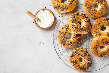 Fresh baked sourdough New York style bagels with cream cheese on light gray table, top view