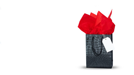 Black gift bag with red tissue paper and white label isolated on white with soft shadow. Banner image