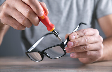 Optical technician repairing eyeglasses with screwdriver.