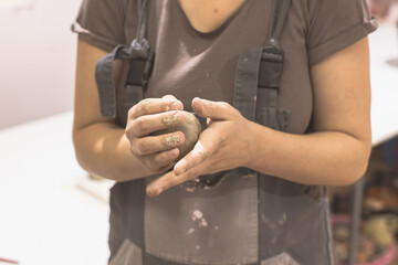 Female pottery artist preparing clay for molding. Close Up view of woman hands with clay. Creative handmade craft