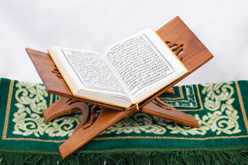 the holy book al quran and prayer rug isolated on white background