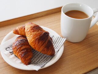 ウッドトレーにのせられたカフェオレとクロワッサン