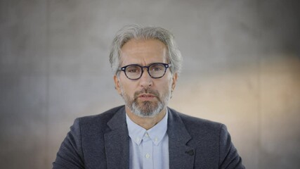 Mature man looking at camera and intently listening. Serious face expression of grey haired businessman. Head and shoulders footage.