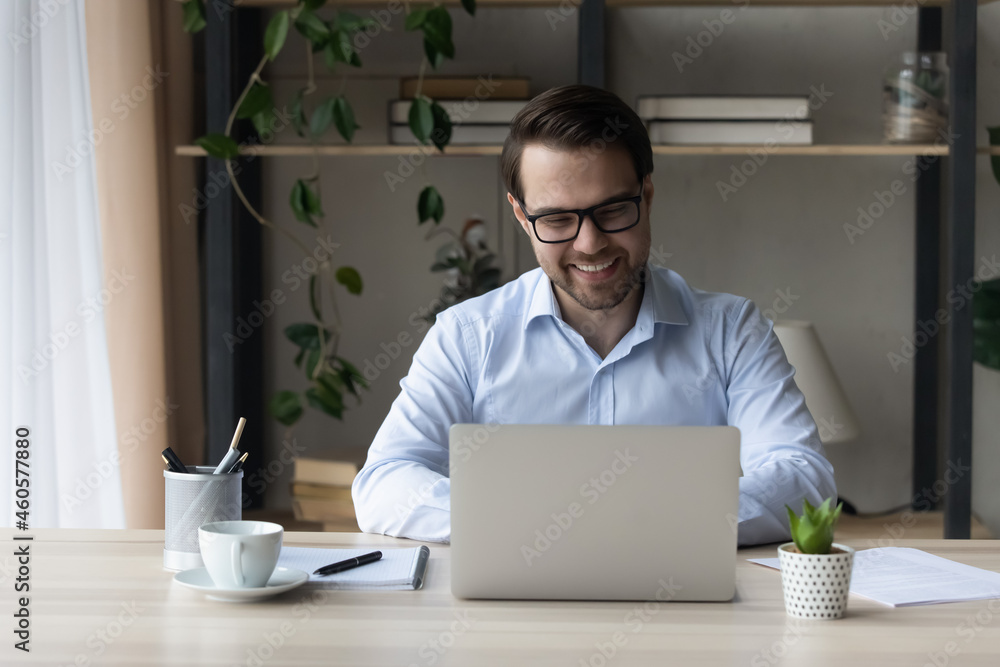 Sticker smiling confident businessman in glasses working on laptop online, sitting at home office desk, look