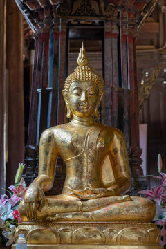 Ancient gilded Buddha statue with gold leaf inside historic Wat Phan Tao buddhist temple, Chiang Mai, Thailand
