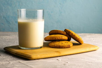 oatmeal cookies and a glass of milk on a wooden cutting board on the table