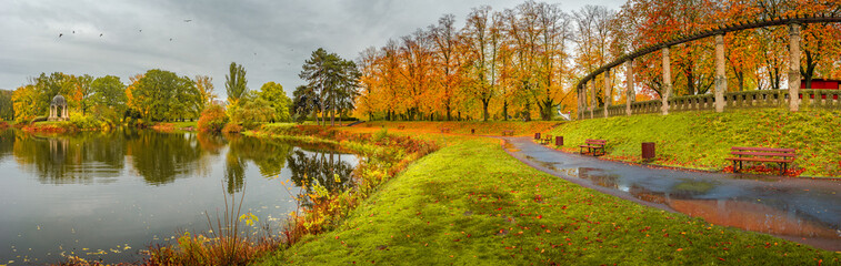 Panoramic view over city park Rotehorn and lake in Autumn golden colors at cloudy rainy day, Magdeburg, Germany.