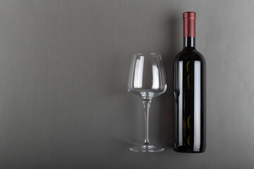 Corked bottle of red wine and empty wine glass on gray background. Alcoholic drink. Winemaking concept. Space for text.