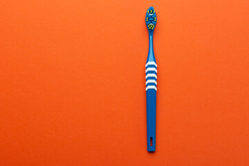 Toothbrush on orange background. Hygiene of the oral cavity. Top view.